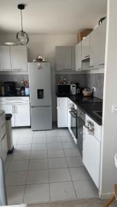 a kitchen with white cabinets and a white refrigerator at Apparentement proche Paris avec terrasse vue dégagée in Bezons