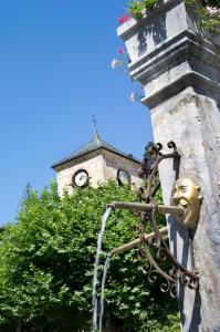 une tête en bronze sur le côté d'un bâtiment avec une tour d'horloge dans l'établissement Hôtel Alexane, à Samoëns