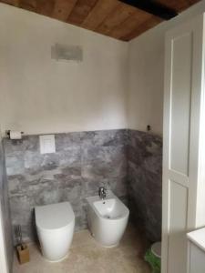 La salle de bains est pourvue de toilettes blanches et d'un lavabo. dans l'établissement Casa vacanza nel verde, à San Clemente in Valle