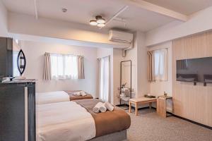 ein Schlafzimmer mit zwei Betten und einem Flachbildfernseher in der Unterkunft b&通天閣店 in Osaka