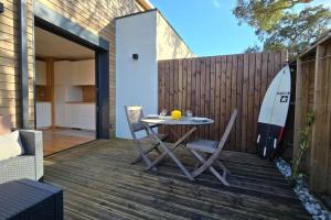 a table and chairs on a deck with a surfboard at Villa Cocoon Contis pour 2 - Jardin privatif - 900m Océan in Lit-et-Mixe