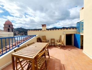 Un balcón con una mesa y sillas en un tejado. en Appartement T6. Emplacement et vue mer d'exception, en Collioure