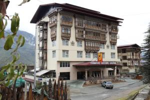 ein Gebäude mit einem davor geparkt in der Unterkunft Thimphu Deluxe Hotel in Thimphu