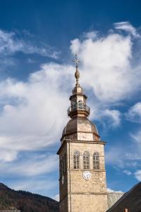 a clock tower with a cross on top of it at Le Roc Des Tours in Le Grand-Bornand