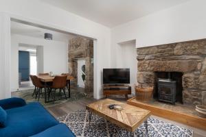 a living room with a blue couch and a stone fireplace at Marazion Charming Retreat for 6 with Social Garden in Marazion