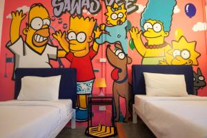 two beds in a room with a mural of simpsons at BW Thai Art Style Hotel in Bangkok