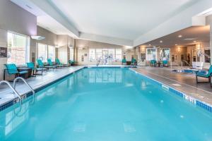 Residence Inn Duluth في دولوث: مسبح كبير مع كراسي وطاولات في فندق