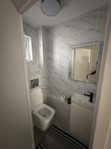 a white bathroom with a toilet and a sink at Brand new suit room 10 min to walk central line! in Woodford