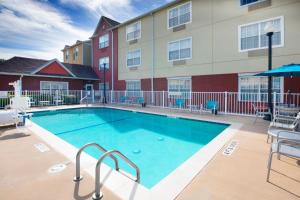 einen Pool mit Stühlen und ein Gebäude in der Unterkunft TownePlace Suites Fort Worth Southwest TCU Area in Fort Worth