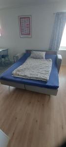 un letto blu in una camera con pavimento in legno di Varjjatgeainu Apartment Nesseby a Varangerbotn