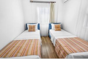 two beds in a small room with a window at Dibek Homes Villa & Hotel in Yalıkavak