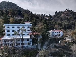 a white building in front of a mountain at The Mountain Quail in Mussoorie