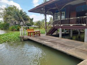 a house with a table on a dock next to the water at หนำเคียงคลอง ฟาร์มสเตย์ Kiangklong Farmstay in Ban Bang Pho