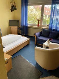 een slaapkamer met een bed, een bank en een stoel bij Gasthaus Rogge in Lemgo