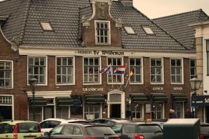 een groot bakstenen gebouw met twee vlaggen erop bij Herberg de Wildeman in Lemmer