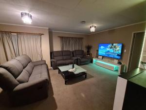 a living room with a couch and a flat screen tv at Hilltop Blue Sky House in Porirua