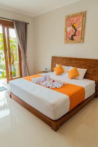 Schlafzimmer mit einem großen Bett mit orangefarbener und weißer Bettwäsche in der Unterkunft Villa Nugraha Lovina Private Pool in Singaraja
