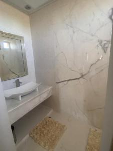 a white bathroom with a sink and a mirror at Dar Lily, villa familiale avec piscine et services in Skoura