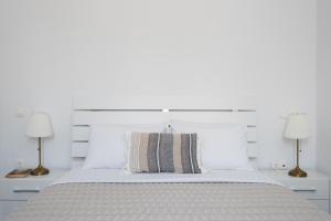 ein weißes Schlafzimmer mit einem großen Bett mit zwei Lampen in der Unterkunft Villa Irini in Platis Gialos Sifnos