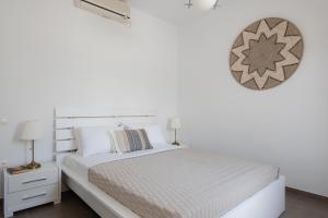 a white bedroom with a bed and a clock on the wall at Villa Irini in Platis Gialos