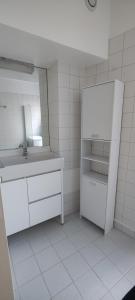 een witte badkamer met een wastafel en een spiegel bij Appartement Cosy Suresnes in Suresnes