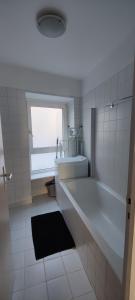 een witte badkamer met een bad en een raam bij Appartement Cosy Suresnes in Suresnes
