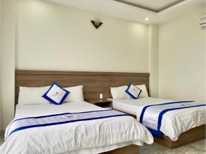 a bedroom with two beds with blue and white sheets at Khách Sạn TRẦN LONG in Ho Chi Minh City