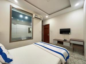 a hotel room with a bed and a television at Khách Sạn TRẦN LONG in Ho Chi Minh City