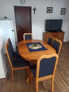 a wooden table with chairs and a plate of food on it at Apartmani Mirjana in Ždrelac