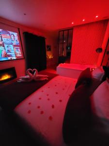 un soggiorno con una camera rossa con divano e TV di Nuit d'évasion love room avec baignoire balnéothérapie a Tolone