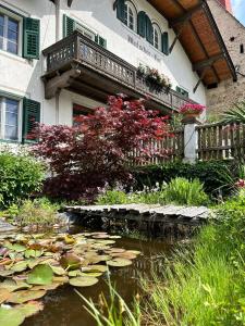 un jardin avec un étang et un bâtiment avec un balcon dans l'établissement Matscherhof Lana, à Lana
