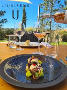 een bord eten op een tafel met wijnglazen bij Hôtel La Bastide d'Iris in Vagnas