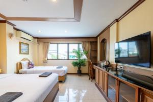 a hotel room with two beds and a flat screen tv at La Casa South Pattaya Hotel in Pattaya South