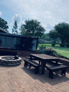 a picnic table and a fire place in a park at Up The Hill Guesthouse in Kestell