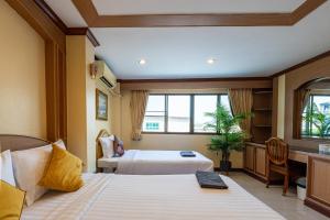 a hotel room with two beds and a window at La Casa South Pattaya Hotel in Pattaya South