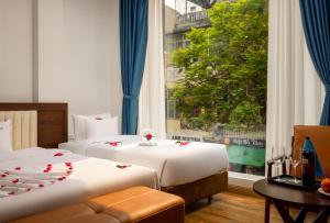 a hotel room with two beds and a window at Casa Valentina Hanoi Hotel in Hanoi