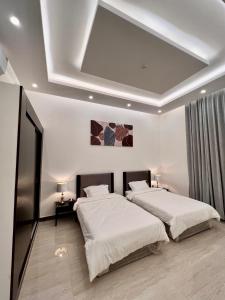 twee bedden in een slaapkamer met een schuin plafond bij مارينا نجد للشقق الفندقية in Hotat bani tamim