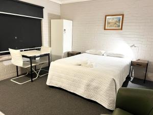 Dormitorio con cama, escritorio y TV en Bairnsdale Town Central Motel, en Bairnsdale