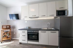 La cuisine est équipée de placards blancs, d'un évier et d'un réfrigérateur. dans l'établissement Sirius Apartments, à Bol