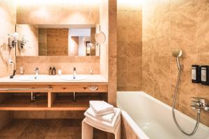 a bathroom with a sink and a tub and a mirror at Naturhotel Leitlhof in San Candido