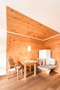 Cette chambre est dotée d'un mur en bois avec une table et des chaises. dans l'établissement Naturhotel Leitlhof, à San Candido