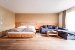 1 dormitorio con 1 cama y 1 sofá azul en Naturhotel Leitlhof, en San Candido