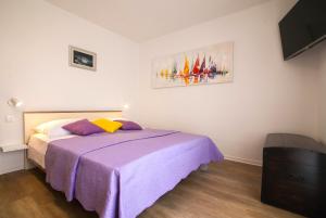 - une chambre avec un lit et une couverture violette dans l'établissement Sirius Apartments, à Bol