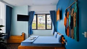 a blue bedroom with a bed and a window at Catba Pod Hostel in Cat Ba