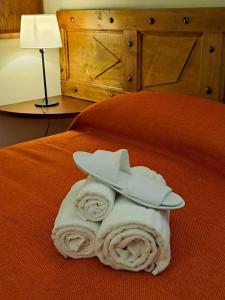 - une pile de serviettes avec un chapeau sur le lit dans l'établissement Oryza Casa di Ringhiera, à Desana