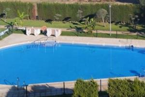 una mujer sentada en una silla junto a una piscina en Casa en Ruta de la Plata con piscina comunitaria, en Guillena