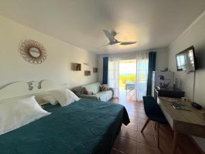 a bedroom with a green bed and a desk and a table at Studio Ti Karanbol RDC vue mer dans Résidence de Tourisme in Sainte-Anne