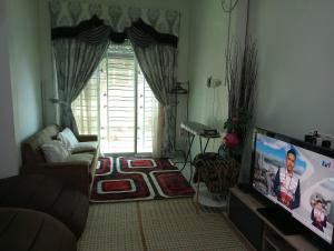 a living room with a couch and a flat screen tv at Villa Fairuz Hana Islamic Stay in Kangar