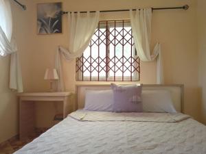 een slaapkamer met een bed en een raam met witte lakens bij Kim's Guest House in Kasoa