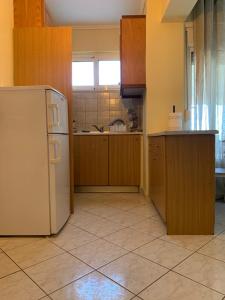 cocina con armarios de madera y nevera blanca en Christina's Home, en Kavala